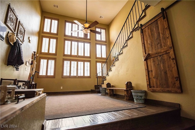 interior space featuring a barn door, a towering ceiling, and ceiling fan