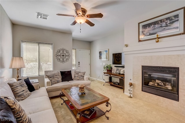 carpeted living room featuring ceiling fan and a tile fireplace