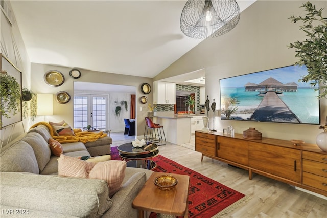 living room with lofted ceiling, french doors, and light hardwood / wood-style floors