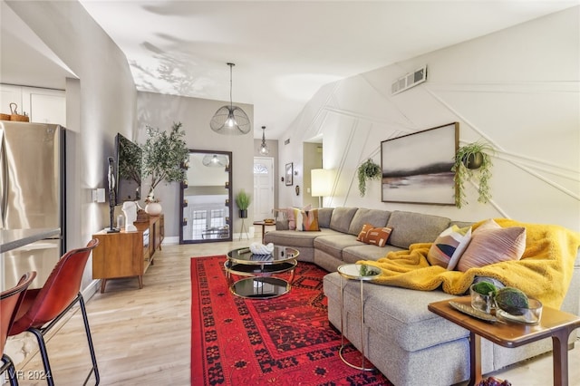 living room with light hardwood / wood-style floors and vaulted ceiling