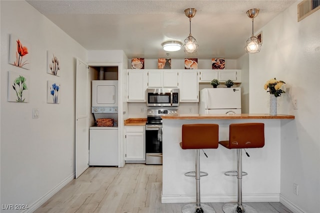 kitchen featuring appliances with stainless steel finishes, a breakfast bar area, pendant lighting, and white cabinets