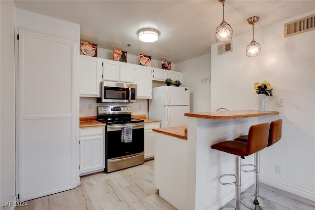 kitchen with light wood-type flooring, a kitchen bar, white cabinetry, and stainless steel appliances