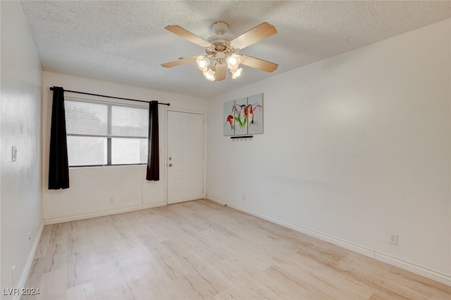 empty room featuring a textured ceiling, light hardwood / wood-style flooring, and ceiling fan