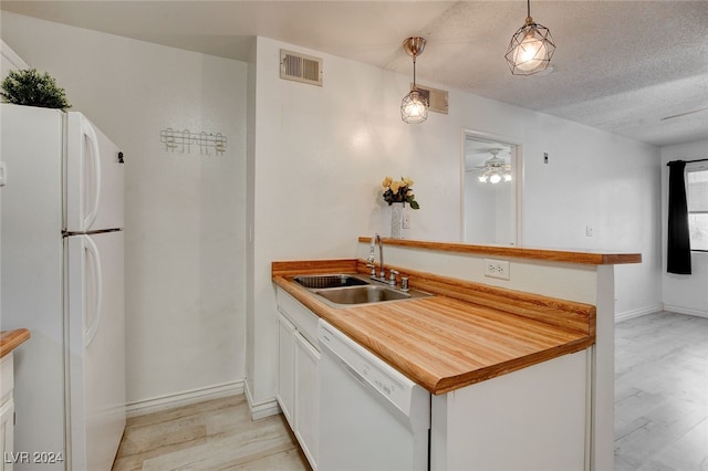 kitchen featuring sink, light hardwood / wood-style flooring, white appliances, a textured ceiling, and pendant lighting