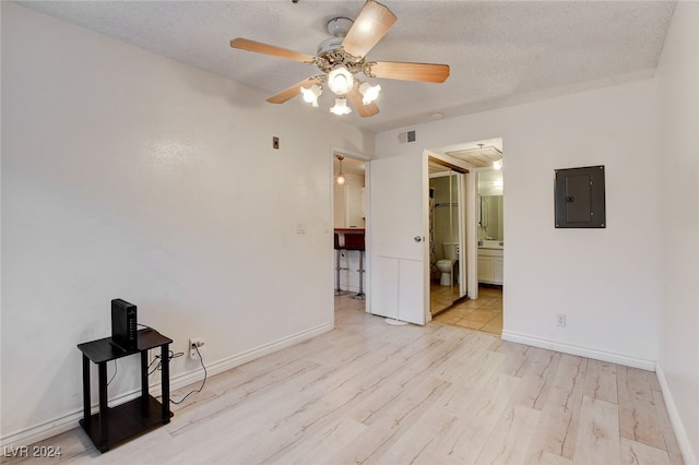 unfurnished room featuring a textured ceiling, light hardwood / wood-style flooring, ceiling fan, and electric panel