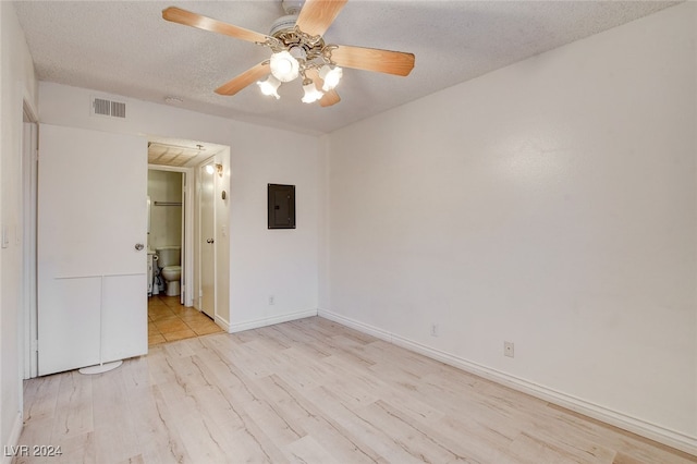 empty room with a textured ceiling, light hardwood / wood-style flooring, ceiling fan, and electric panel