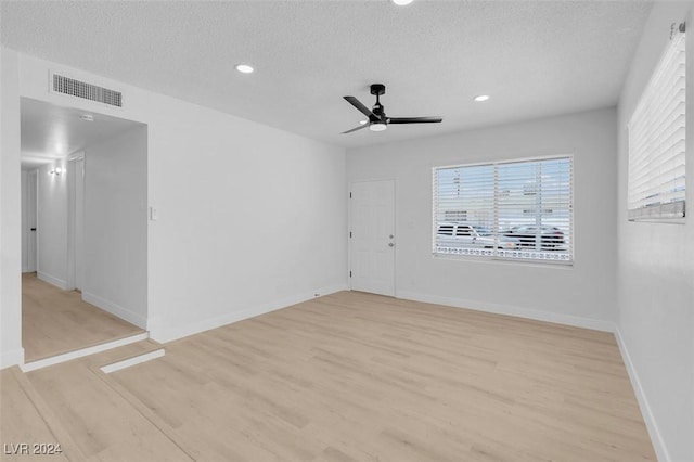 unfurnished room featuring ceiling fan, plenty of natural light, a textured ceiling, and light wood-type flooring