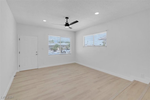 unfurnished room featuring light hardwood / wood-style flooring, plenty of natural light, and a textured ceiling