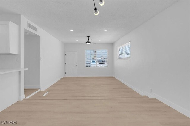 unfurnished room with ceiling fan, light hardwood / wood-style floors, and a textured ceiling