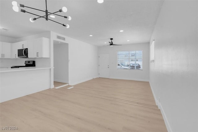 unfurnished living room with ceiling fan with notable chandelier and light hardwood / wood-style floors