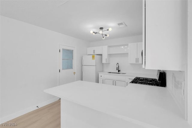 kitchen with sink, stove, white refrigerator, white cabinets, and light wood-type flooring