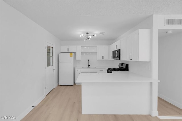 kitchen with sink, stove, white refrigerator, white cabinets, and kitchen peninsula