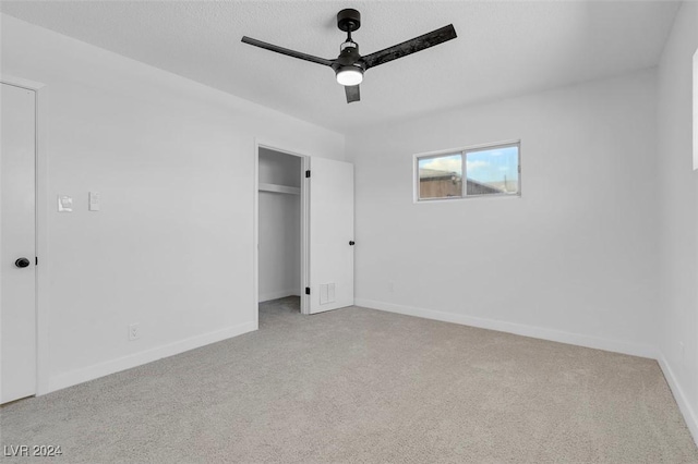 unfurnished bedroom featuring light colored carpet, a textured ceiling, ceiling fan, and a closet