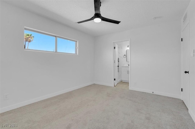 spare room with ceiling fan, light colored carpet, and a textured ceiling