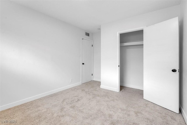 unfurnished bedroom featuring light carpet and a closet