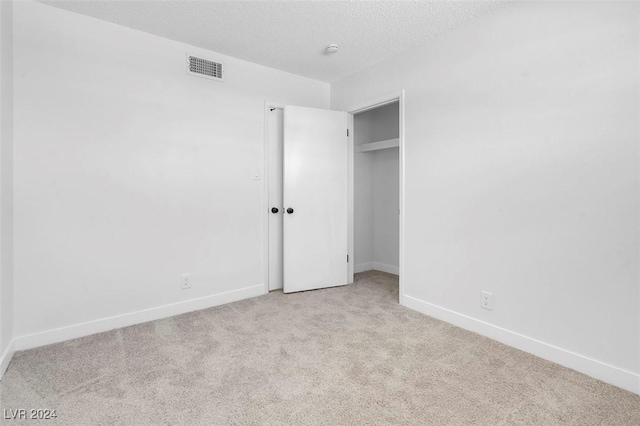 unfurnished bedroom featuring light carpet and a textured ceiling