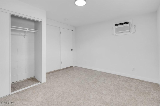 unfurnished bedroom with light carpet, a closet, and a wall mounted AC