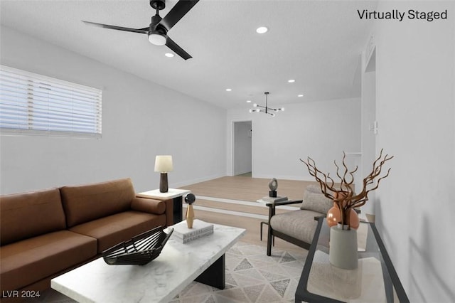 living room with light hardwood / wood-style floors and ceiling fan with notable chandelier