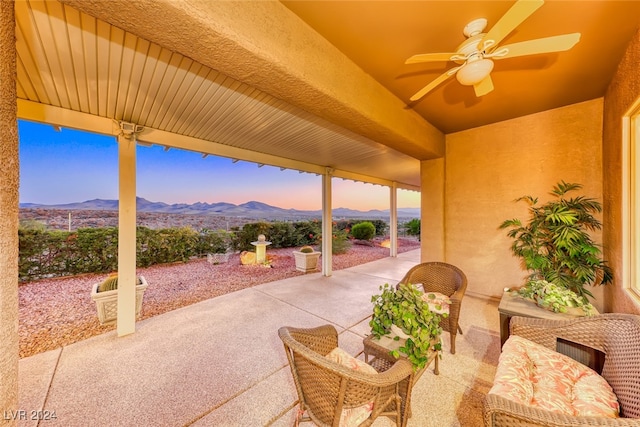 patio terrace at dusk featuring ceiling fan and a mountain view