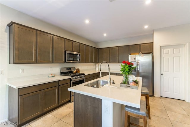 kitchen featuring sink, a breakfast bar area, dark brown cabinetry, stainless steel appliances, and a center island with sink