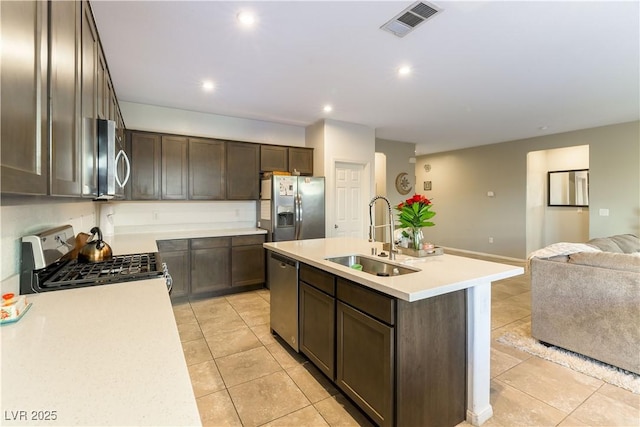 kitchen with appliances with stainless steel finishes, sink, light tile patterned floors, and a kitchen island with sink