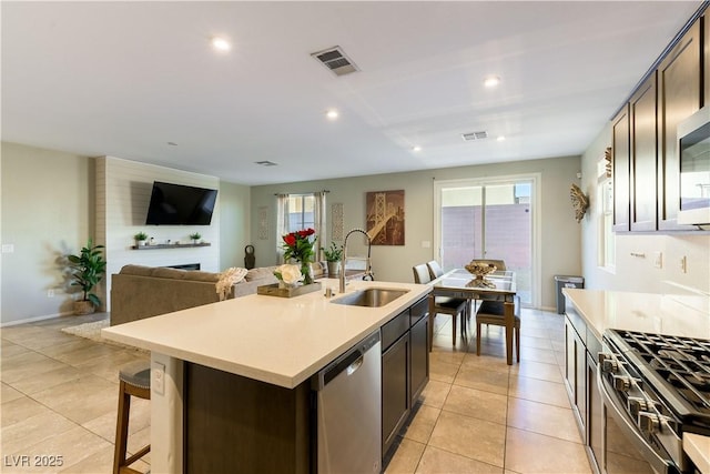 kitchen featuring an island with sink, appliances with stainless steel finishes, sink, and dark brown cabinets