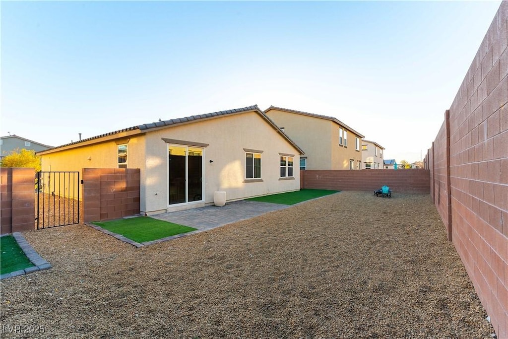 rear view of property with a patio, a gate, a fenced backyard, and stucco siding