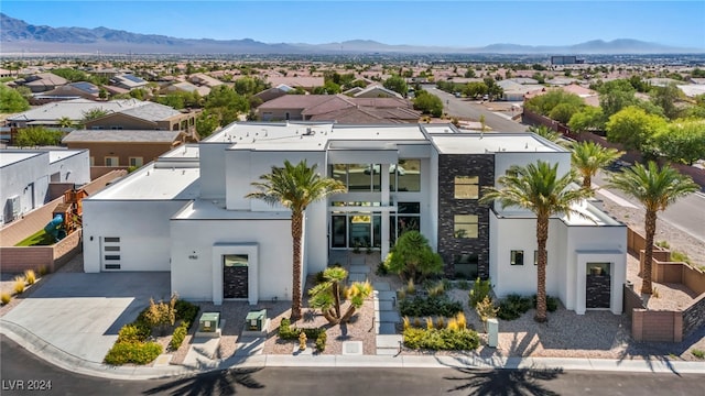 view of front of property with stucco siding, concrete driveway, a mountain view, a garage, and a residential view