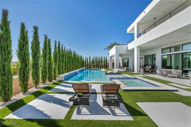 view of pool with a yard, an infinity pool, and a patio