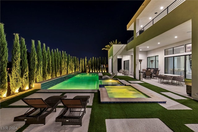 pool at twilight featuring an outdoor pool, a patio, and an in ground hot tub