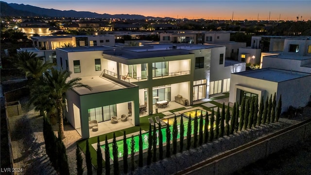 rear view of house featuring stucco siding, a patio, a balcony, and a mountain view