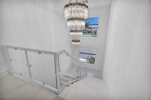 staircase with a wealth of natural light, a towering ceiling, and an inviting chandelier