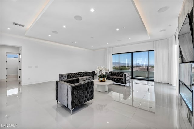 living area with baseboards, a raised ceiling, visible vents, and recessed lighting