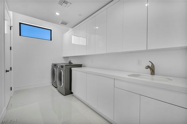 washroom with light tile patterned floors, cabinet space, visible vents, a sink, and independent washer and dryer