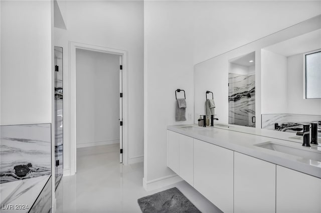 full bath featuring double vanity, a sink, a marble finish shower, and baseboards