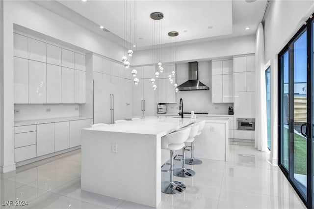 9760 Solar Ave, Las Vegas, NV 89149 - kitchen featuring wall chimney range hood, modern cabinets, light tile patterned floors, a breakfast bar area, and white cabinets