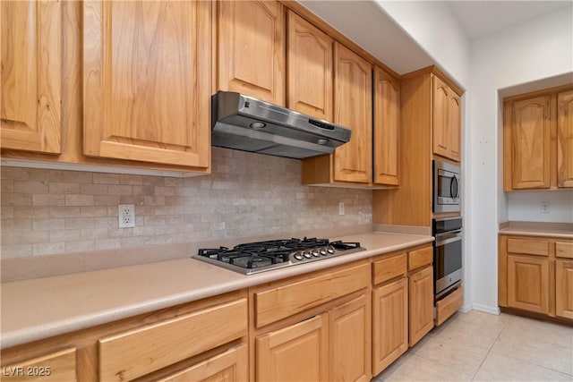 1629 Black Fox Canyon Rd, Henderson, NV 89052 - kitchen with under cabinet range hood, stainless steel appliances, decorative backsplash, and light countertops
