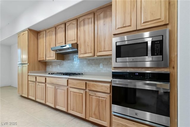 1629 Black Fox Canyon Rd, Henderson, NV 89052 - kitchen featuring appliances with stainless steel finishes, light brown cabinetry, under cabinet range hood, light countertops, and backsplash