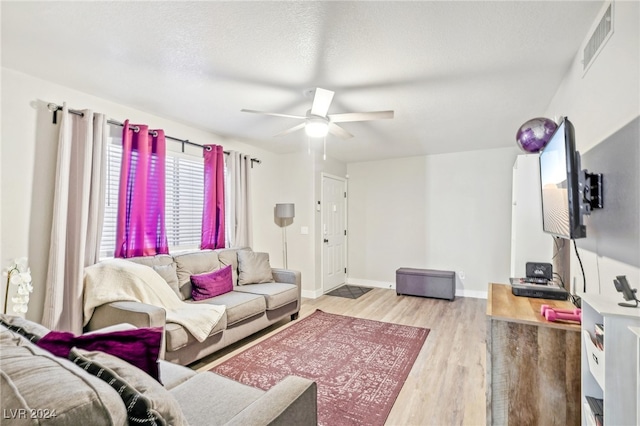 living room with a textured ceiling, light hardwood / wood-style floors, and ceiling fan