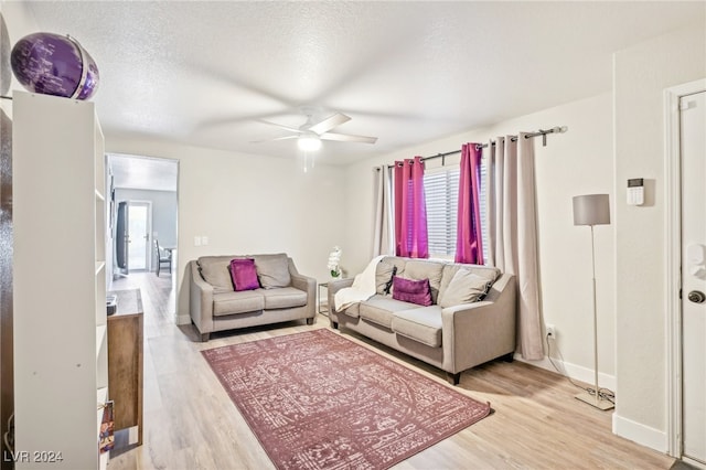 living room with ceiling fan, a textured ceiling, and light hardwood / wood-style flooring