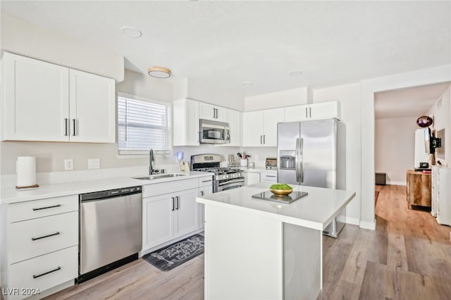 kitchen with light hardwood / wood-style floors, a center island, sink, white cabinetry, and appliances with stainless steel finishes