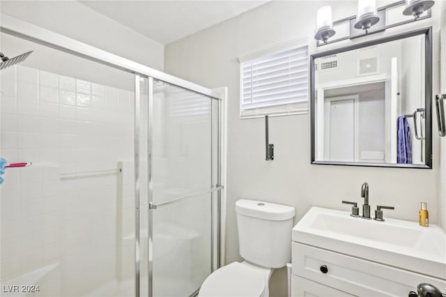 bathroom featuring vanity, a shower with shower door, and toilet