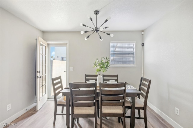 dining area featuring an inviting chandelier, light hardwood / wood-style floors, and a textured ceiling