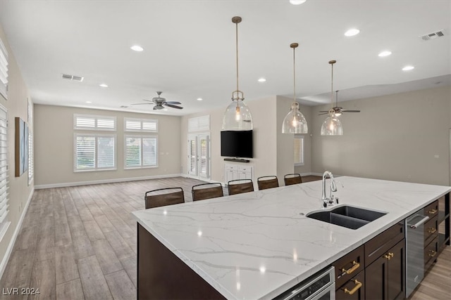 kitchen with ceiling fan, sink, a kitchen island with sink, and light hardwood / wood-style flooring