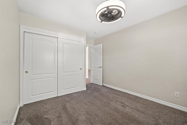 unfurnished bedroom featuring a closet and dark carpet