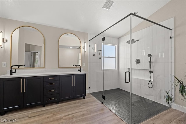 bathroom with vaulted ceiling, vanity, wood-type flooring, and a shower with shower door