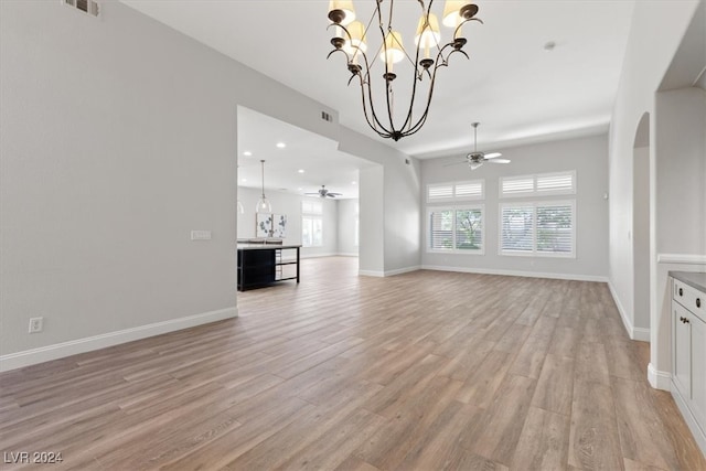 unfurnished living room with ceiling fan with notable chandelier and light wood-type flooring