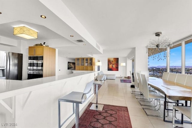 kitchen featuring a breakfast bar area, visible vents, appliances with stainless steel finishes, open floor plan, and light tile patterned flooring