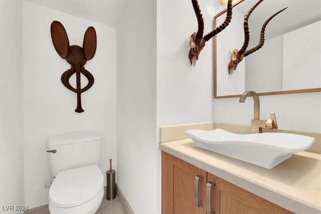 bathroom with toilet, vanity, and tile patterned floors