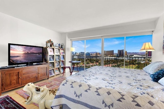 bedroom with access to exterior, a view of city, and light wood-style flooring